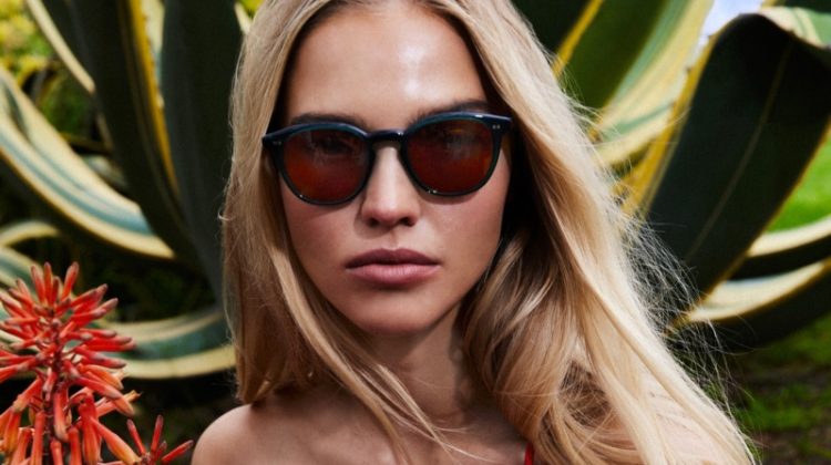 Model Sasha Luss models Oliver Peoples Desmon Sun for the brand's summer 2023 campaign.