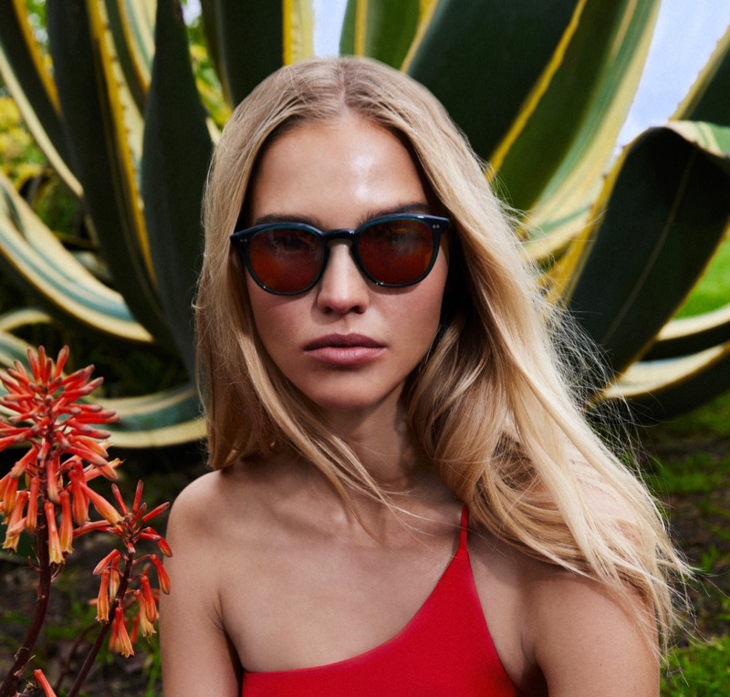 Model Sasha Luss models Oliver Peoples Desmon Sun for the brand's summer 2023 campaign.