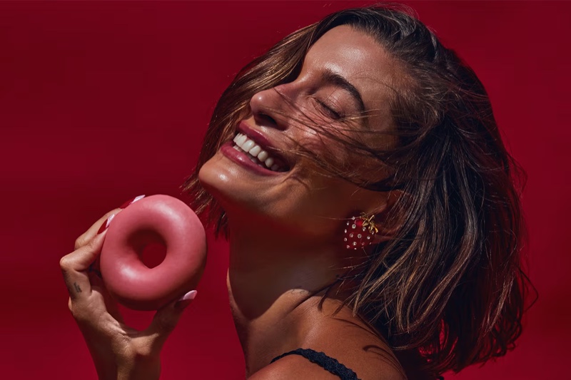 Posing with a donut, Hailey Bieber delivers glossy beauty with Rhode's latest addition.