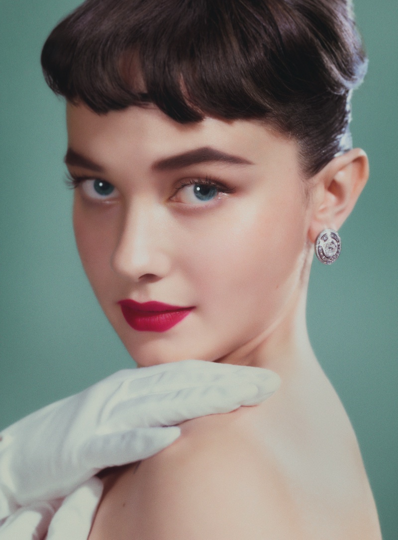 Posing as Audrey Hepburn, Cailee Spaeny wears red lipstick with Bulgari earrings.