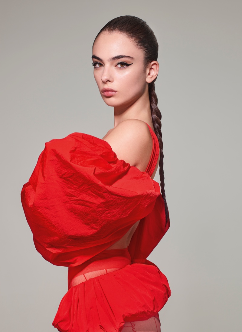 Actress and model Deva Cassel strikes a bold pose in a voluminous red ensemble from Jacquemus, her hair styled in a sleek braid.