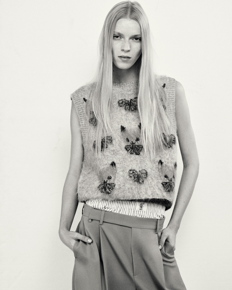Harry Lambert's Zara collaboration features a butterfly-adorned sweater vest with pleated bottoms.