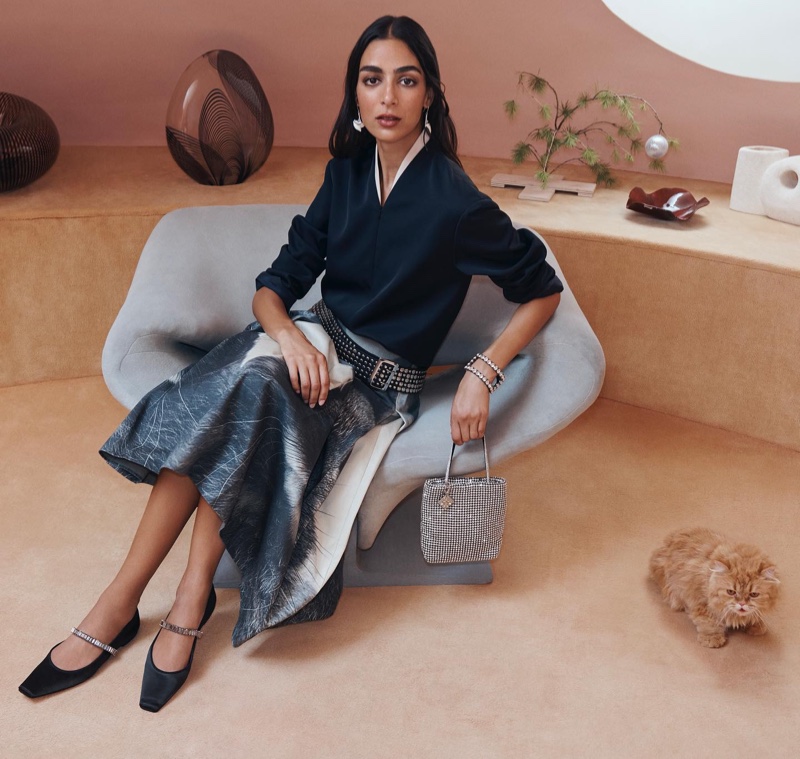 Nora Attal exudes elegance in a blue sweater and flared skirt for Tory Burch's holiday collection.