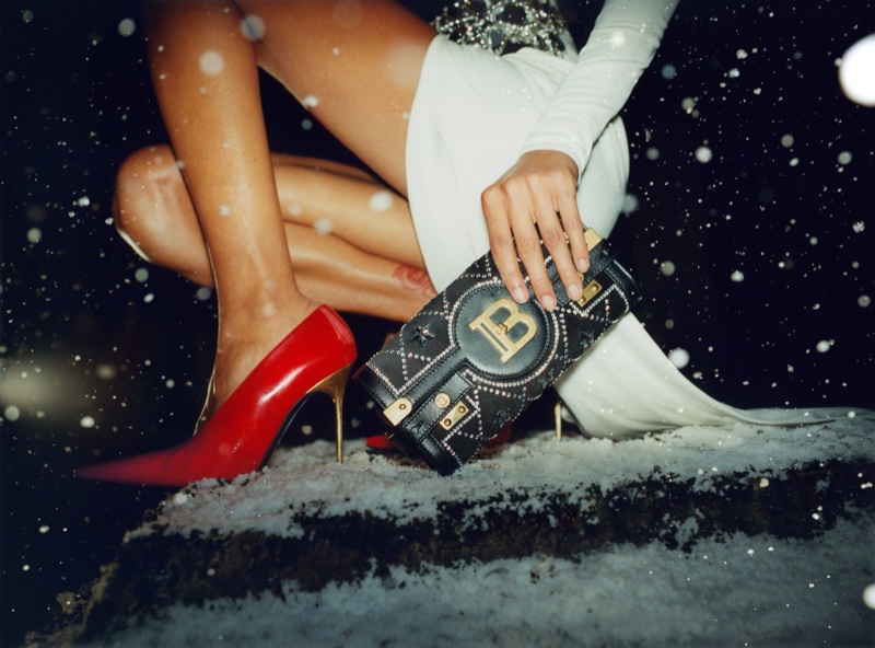 Red heels and a Balmain handbag complement a winter white ensemble for the holiday 2023 season.