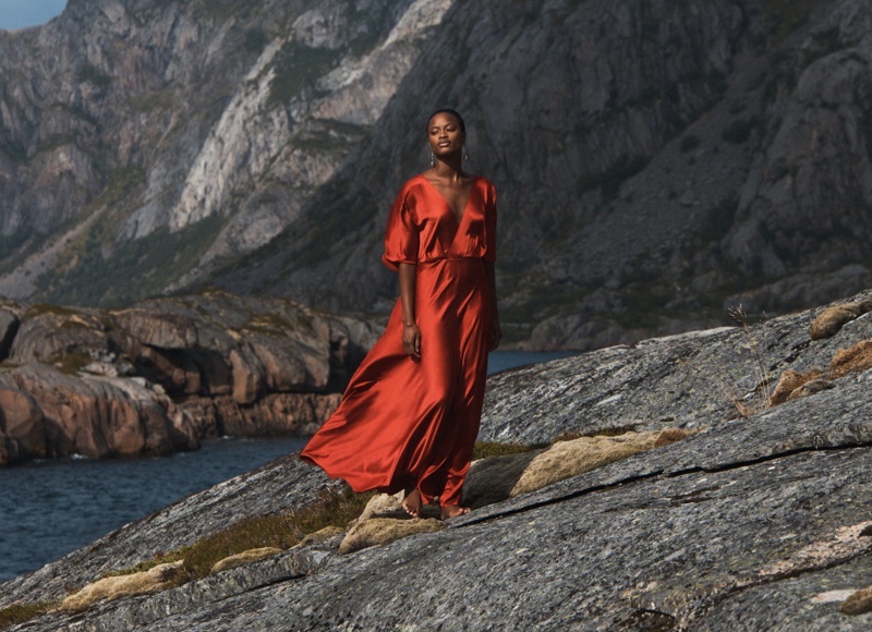 A striking burnt orange gown stands out against the rugged mountain backdrop, embodying the adventurous spirit of Banana Republic's winter collection.