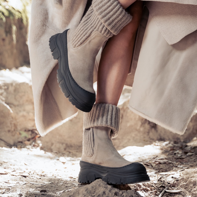 A close-up of Brunello Cucinelli's Chelsea boots with rib-knit cuffs, blending luxury with the ruggedness of winter landscapes.