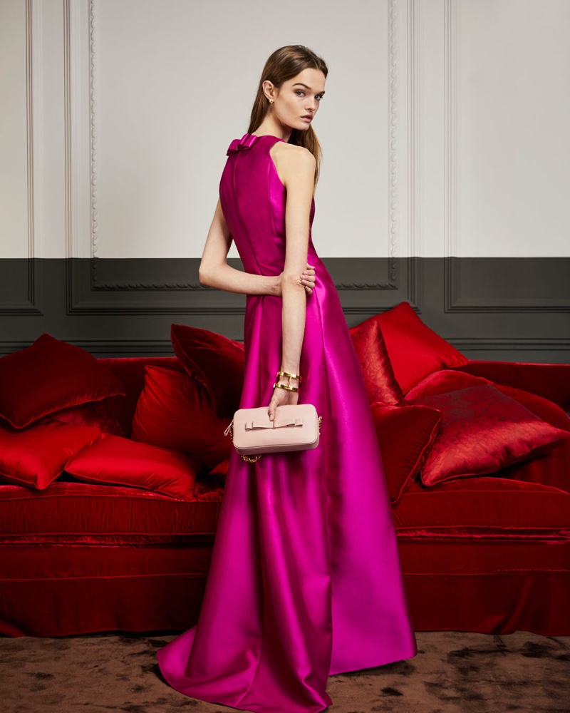 The epitome of glamour unfolds in a striking magenta CH Carolina Herrera gown, gracefully complemented by a chic blush bag for its holiday 2023 gift guide.