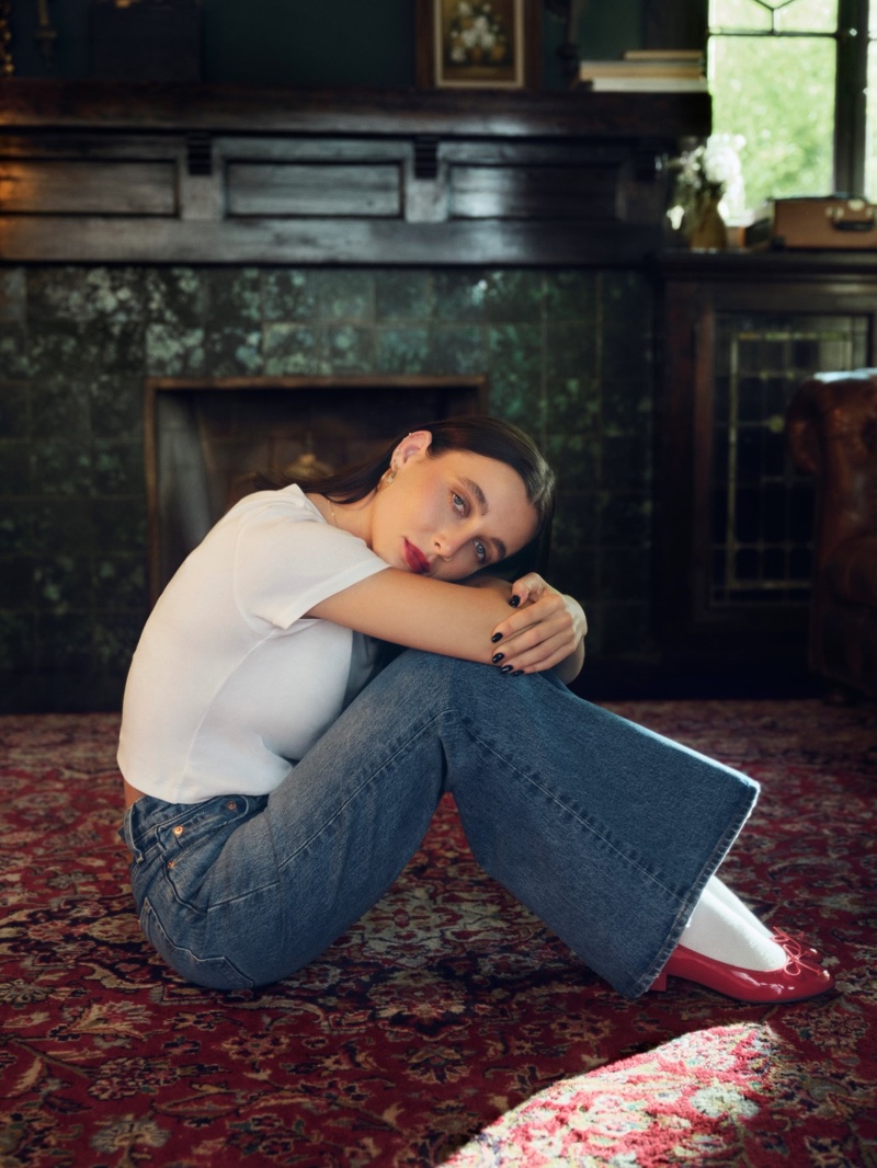 Lounging with red lipstick, Emma Chamberlain brings a touch of effortless elegance to the holidays in Levi's flared jeans paired with a white tee.