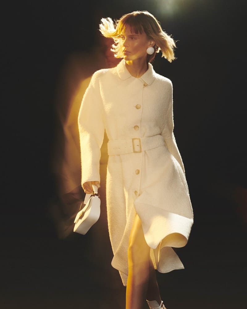 A vision in winter white, Emporio Armani features a coat complemented by statement pearl earrings and a white handbag.
