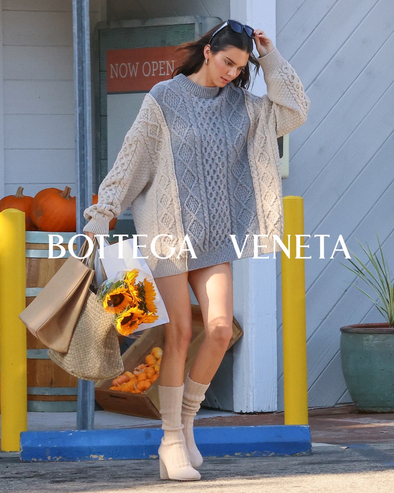 Kendall Jenner embraces relaxed vibes with a cozy oversized sweater, complementing thigh-high knit socks from the Bottega Veneta pre-spring 2024 collection.