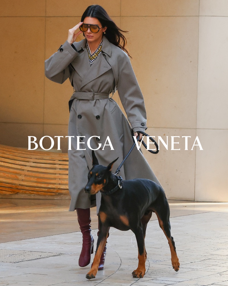 Accompanied by her Doberman, Kendall Jenner cuts a chic figure in a tailored Bottega Veneta trench coat and burgundy boots for the brand's pre-spring 2024 campaign.