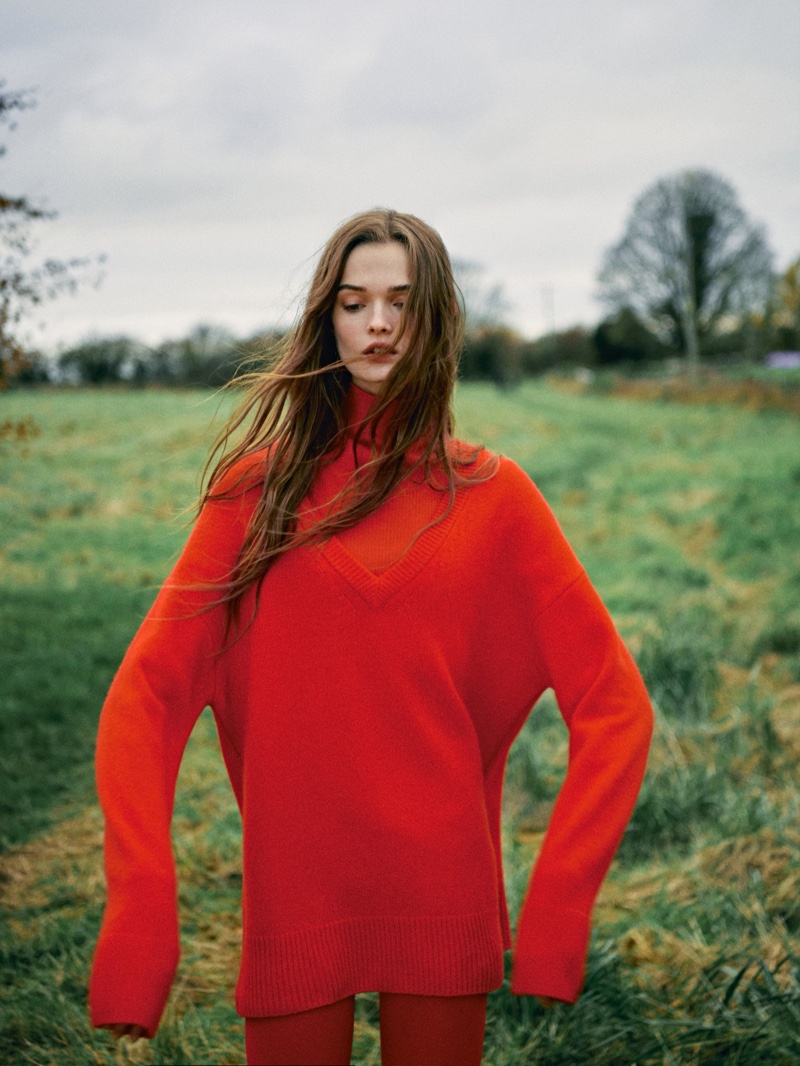 Massimo Dutti features a bright red turtleneck ensemble, bringing a burst of color to a serene, green field in the December collection. 