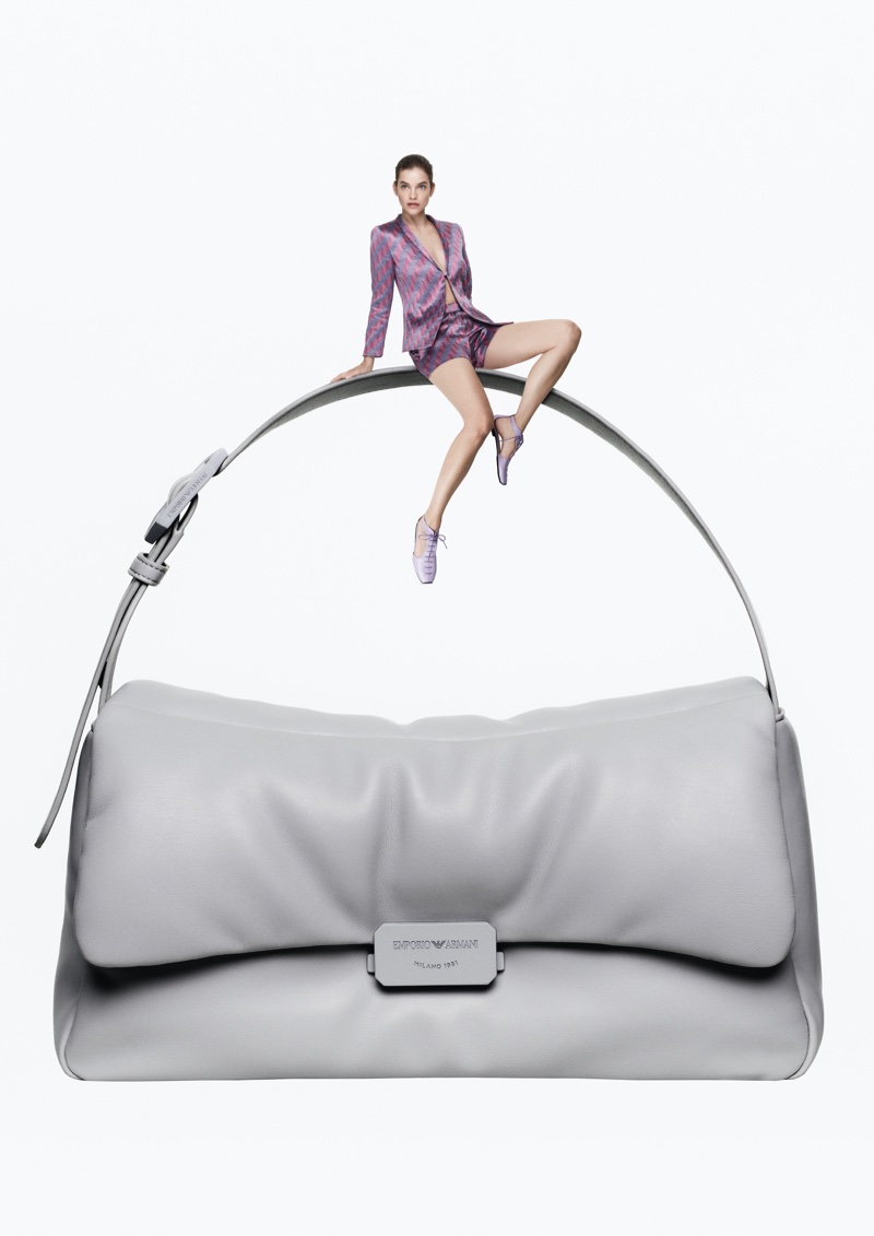 Barbara Palvin poses perched atop an Emporio Armani handbag, for the spring 2024 campaign's play on proportions.