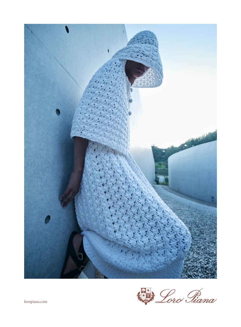 Leaned against modern architecture, Selena Forrest fronts Loro Piana spring 2024 ad in a white crocheted ensemble.