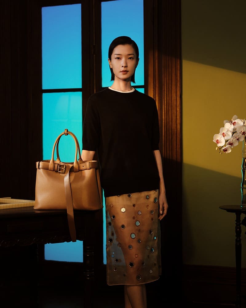 In Prada's Lunar New Year 2024 campaign, Du Juan pairs understated elegance with an embellished skirt and spacious tote.