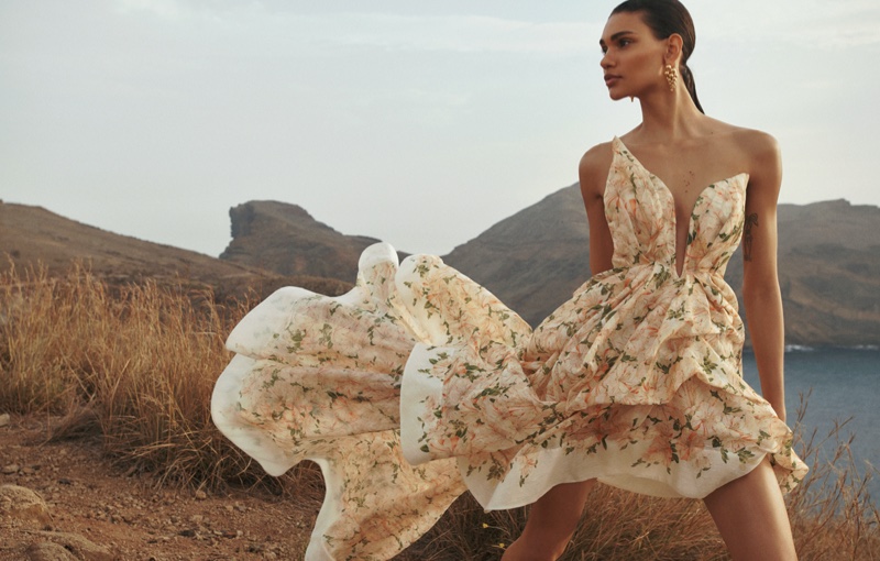 Barbara Valente stands out in a floral print dress, blending with the landscape for Zimmermann's spring 2024 campaign.