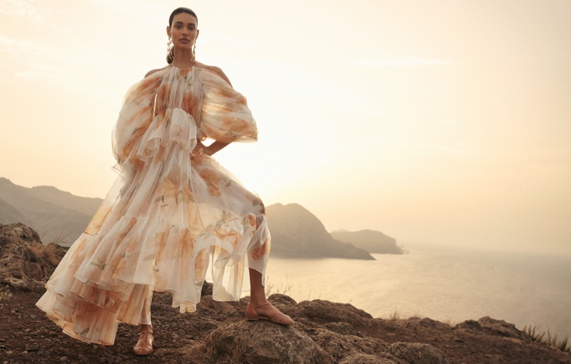 Sheer elegance frames Barbara Valente in a Zimmermann's spring 2024 campaign, amidst the tranquil seascape.