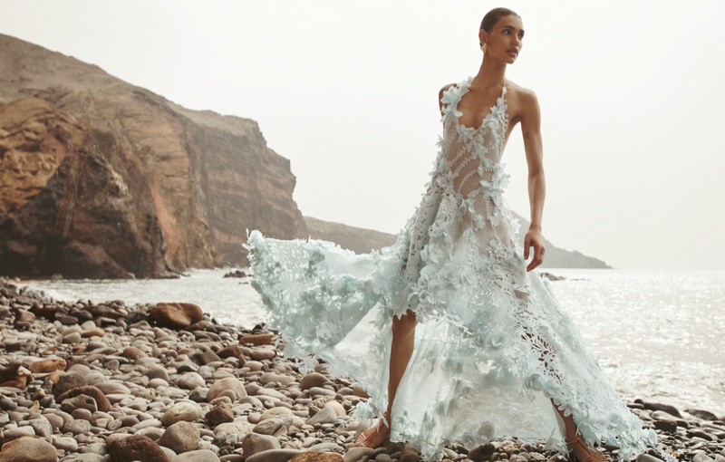Barbara Valente poses in a serene, oceanic Zimmermann gown, where rocks meet sea for spring 2024's campaign.