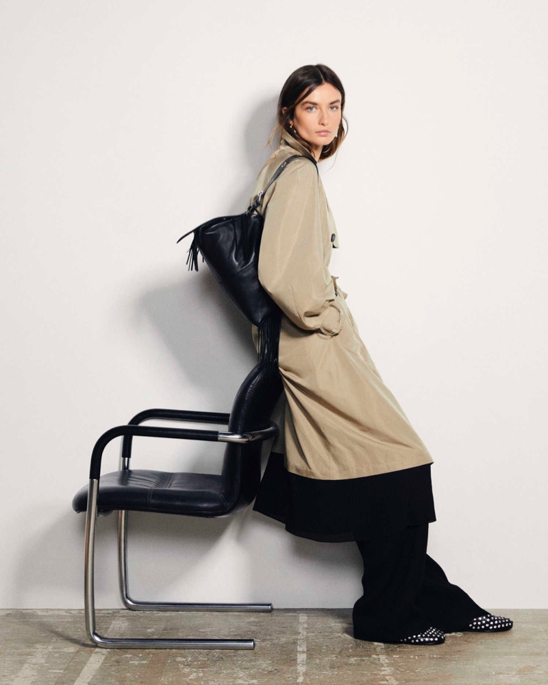 Posing chicly, Andreea Diaconu showcases Maje's classic trench coat for spring-summer 2024.