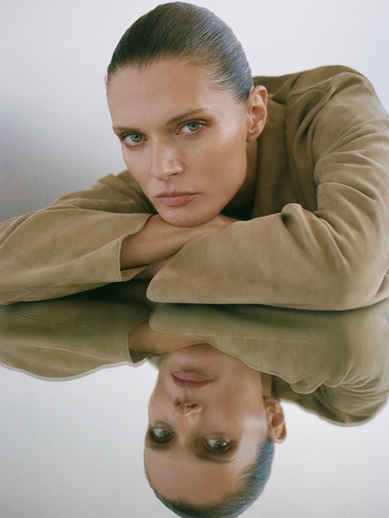 Malgosia Bela exudes understated elegance in a suede Massimo Dutti ensemble, reflecting in a serene, mirrored pose.
