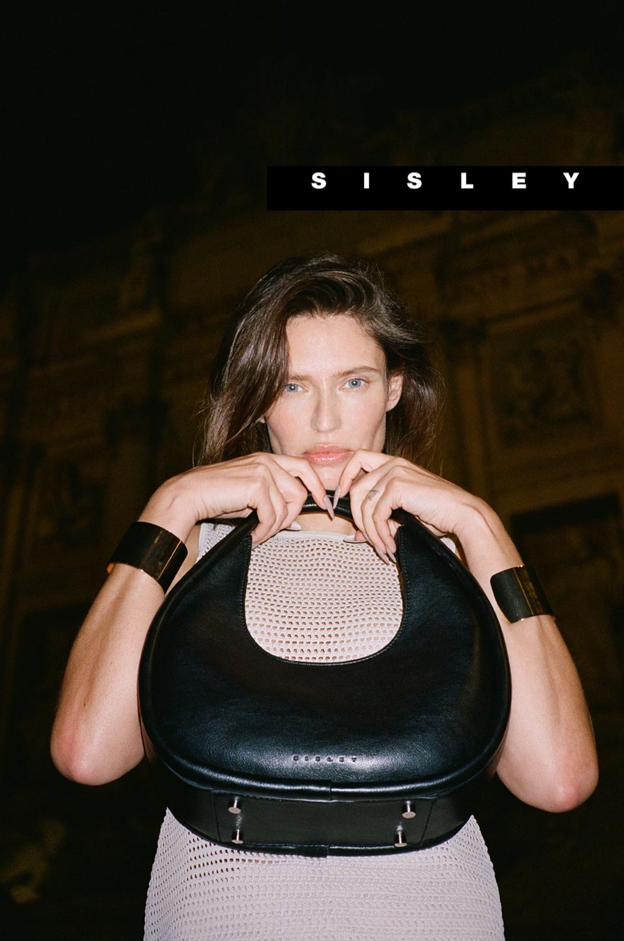 Holding a chic black handbag, Bianca Balti poses in a knit design for the Sisley spring-summer 2024 advertisement.