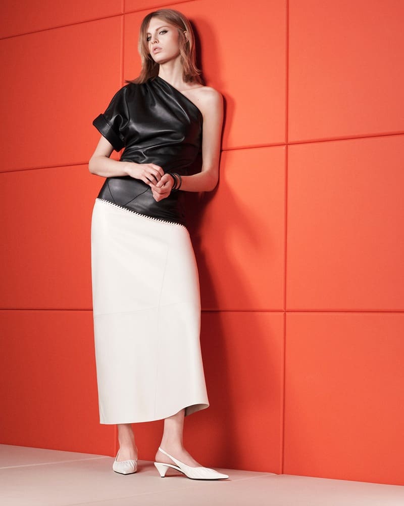 Zara's spring 2024 edit presents a sleek contrast with a one-shoulder leather top and a streamlined white skirt.