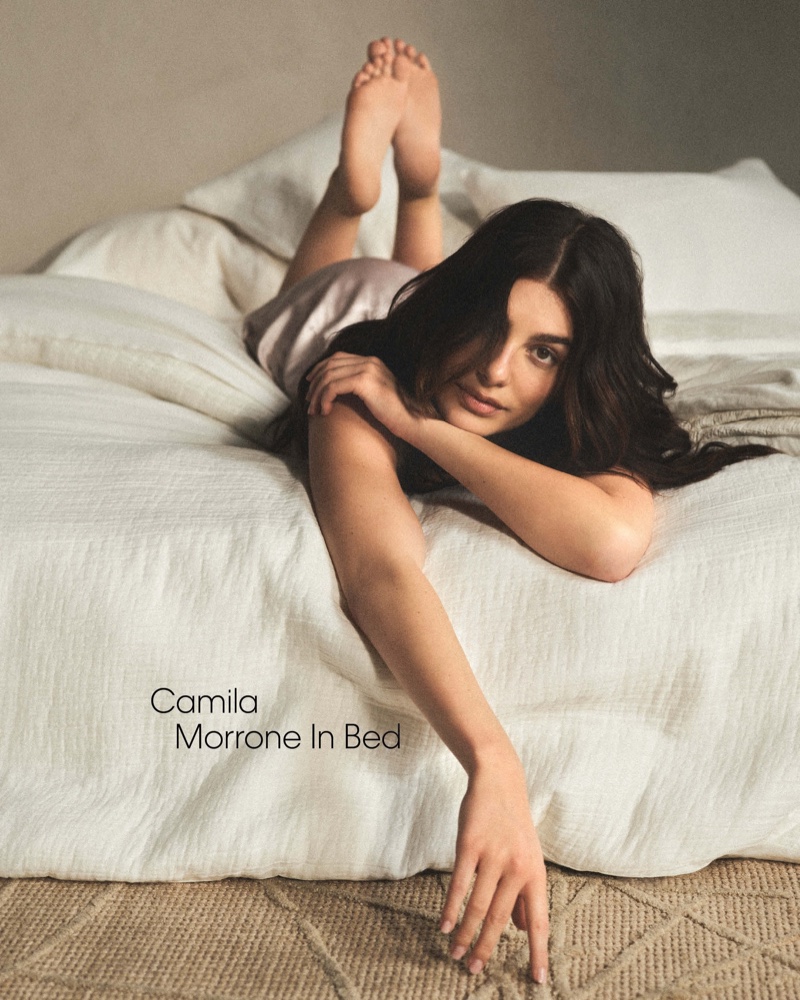 Lying relaxed on a bed, Camila Morrone showcases the soft bedding of Calvin Klein Home's spring 2024 line.