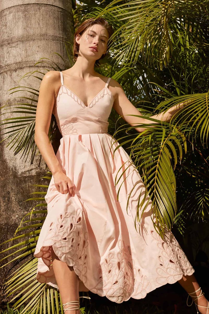 Grace Elizabeth exudes tropical elegance in a blush dress for Cinq à Sept's spring 2024 collection, surrounded by palms.