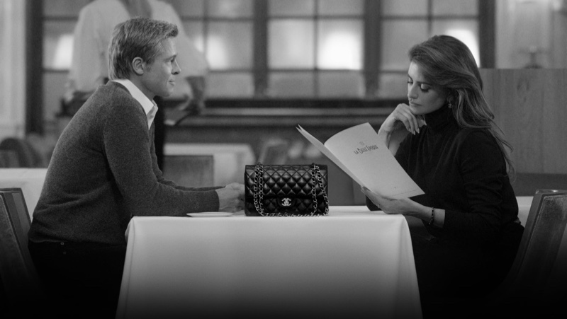 Penélope Cruz takes a glance over the menu with Chanel's iconic Flap bag as the centerpiece with Brad Pitt.