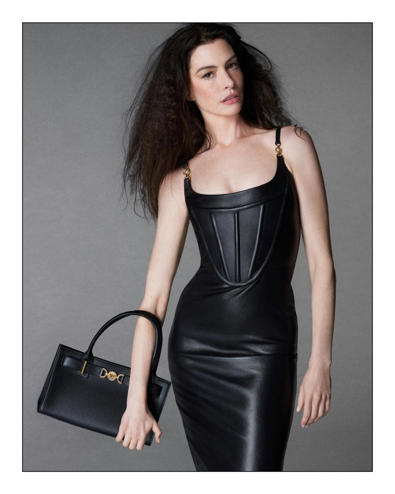 Versace Icons 2024 ad enlists Anne Hathaway to showcase the allure of a sleek leather dress and handbag.