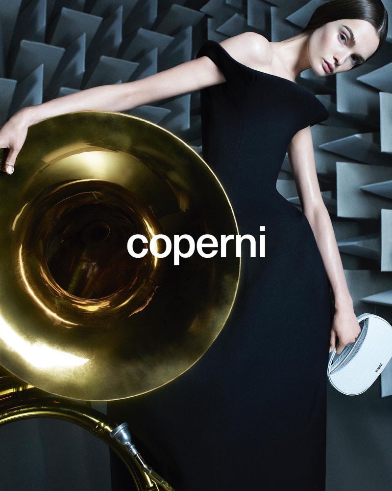 Coperni's spring 2024 campaign features a black dress, complemented by a brass instrument.