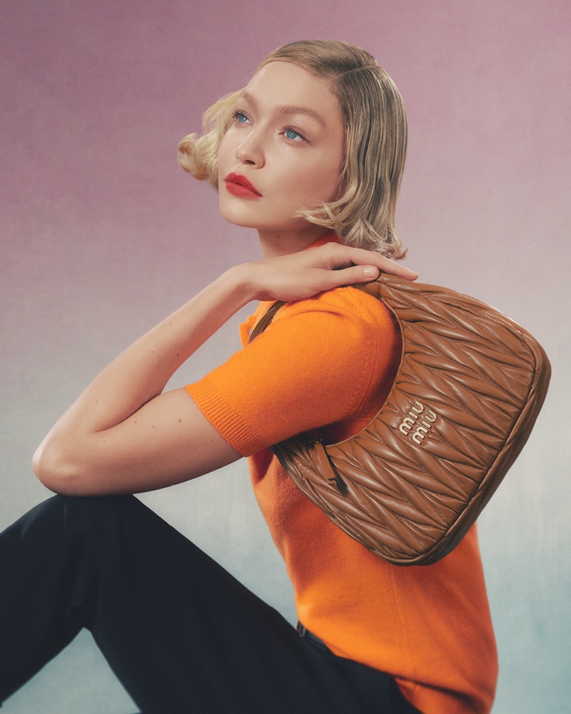 Miu Miu's 2024 handbag campaign comes to life with Gigi Hadid's pop of orange and sleek accessory choice.