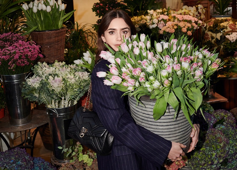 Amidst a floral embrace, Lily Collins complements Cartier's Panthère bag with classic elegance.