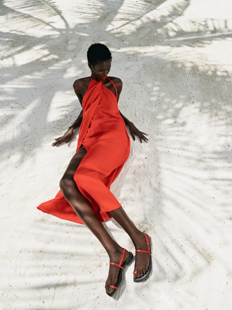 A red Massimo Dutti halter neck dress with pleated detail stands out on the beach.