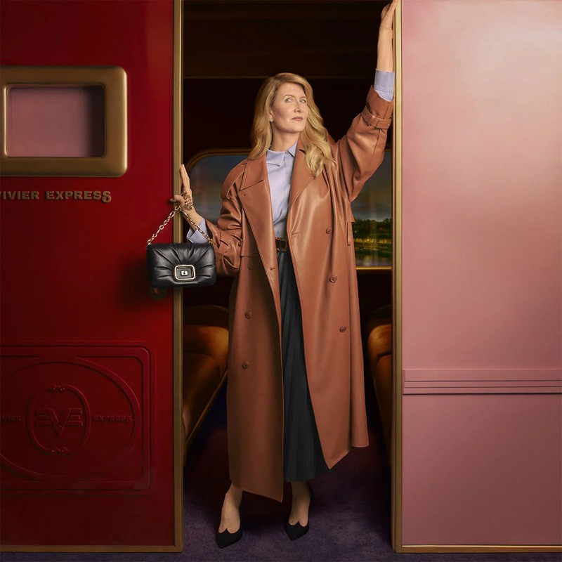 Laura Dern stands gracefully in the doorway of the Roger Vivier Express, clad in a luxurious trench coat.