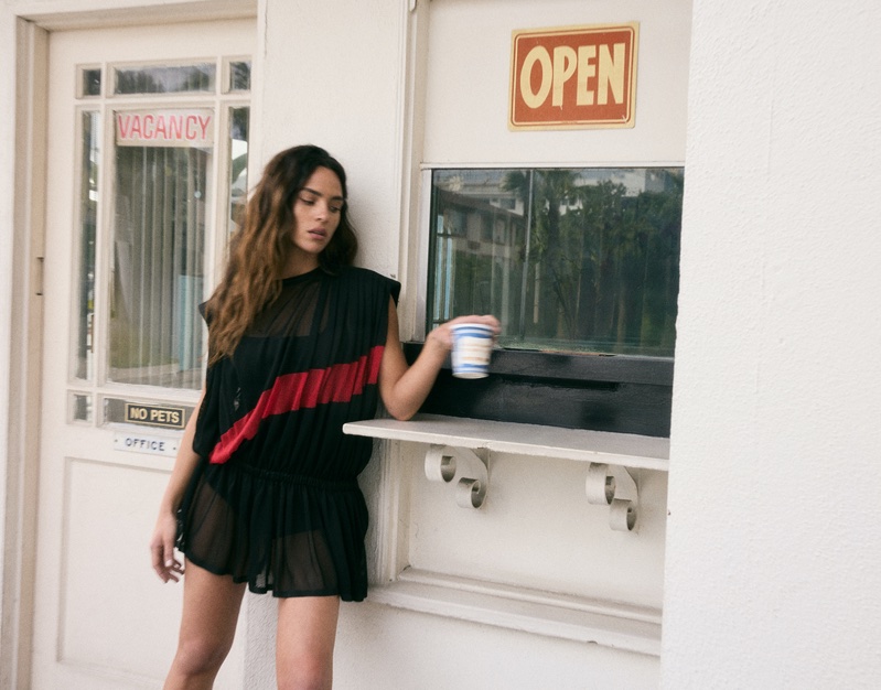 Actress Adria Arjona wears a little black dress with a red accent.